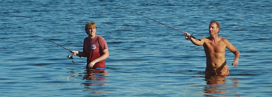 Two guys wade-fishing in water by Sunshine Skyway Bridge in St. Petersburg, Florida.