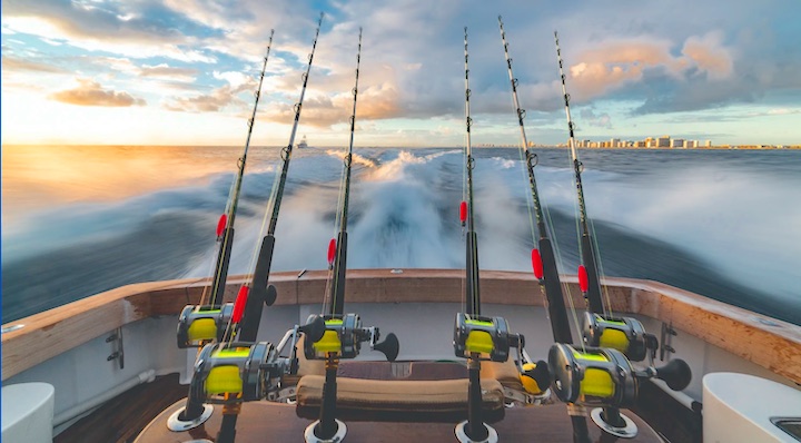 Big saltwater trolling reels facing the back of the boat while moving.