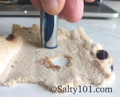 Using pen cap for punching circles in compressed bread for fishing bait.