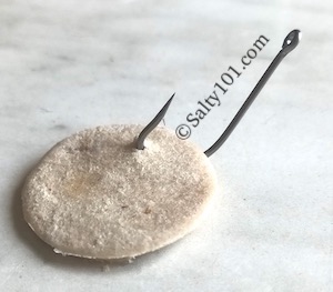 Fishing hook in punched bread piece for baiting hook for fishing.