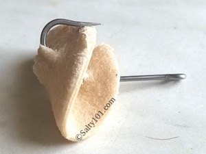 Fishing hook in folded bread piece for fishing.