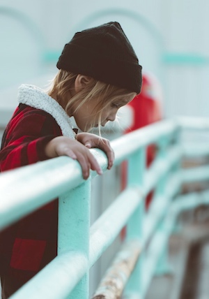 Girl on fishing trip hanging over railing because of feeling ill with sea sickness.