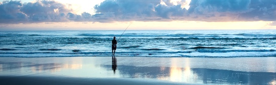 Woman surf fishing at sunset in Florida.